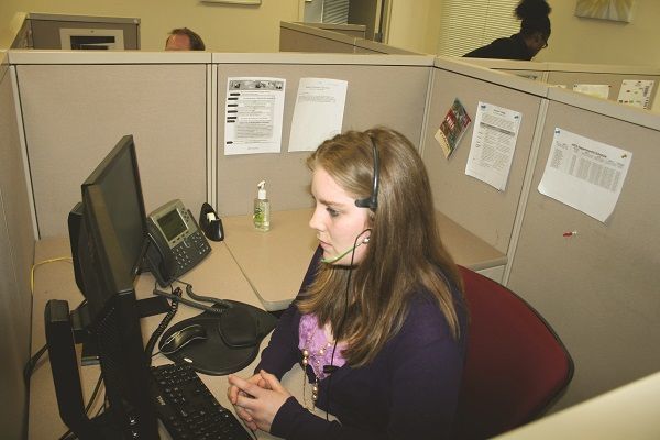 Call Center Operator sitting at desk wearing headset and talking to caller