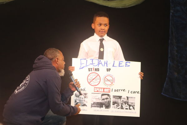 Black boy holding up a handmade poster