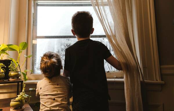 Two children looking out of a house window
