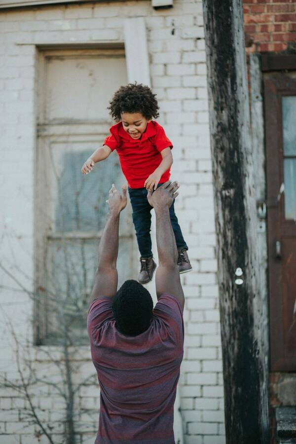 A man playfully tossing a young boy into the air