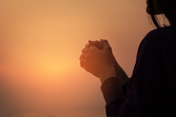 Up close view of hands in prayer position at sunset